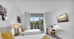 A hotel room with two beds, a desk, a chair, a TV, and a balcony with a view. - Beachwalk Studio | Intracoastal Balcony (Hallandale Beach)