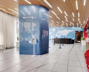 En modern hotellobby med en böjd receptionsdisk, en världskarta p å väggen och en träpanel i taket.