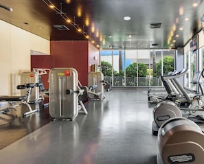 A gym with cardio machines, weight equipment, and large windows offering a view of the outdoors. - Upper-Floor Studio | Resort Pool & Beach (Hallandale Beach)