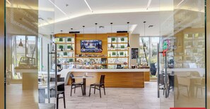 A bar area with a counter, seating, and a TV screen. - Spacious 1BR · Sunset View · Beachwalk Resort (Hallandale Beach)