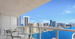 A balcony with a view of a city skyline and a body of water. - Spacious 1BR · Sunset View · Beachwalk Resort (Hallandale Beach)