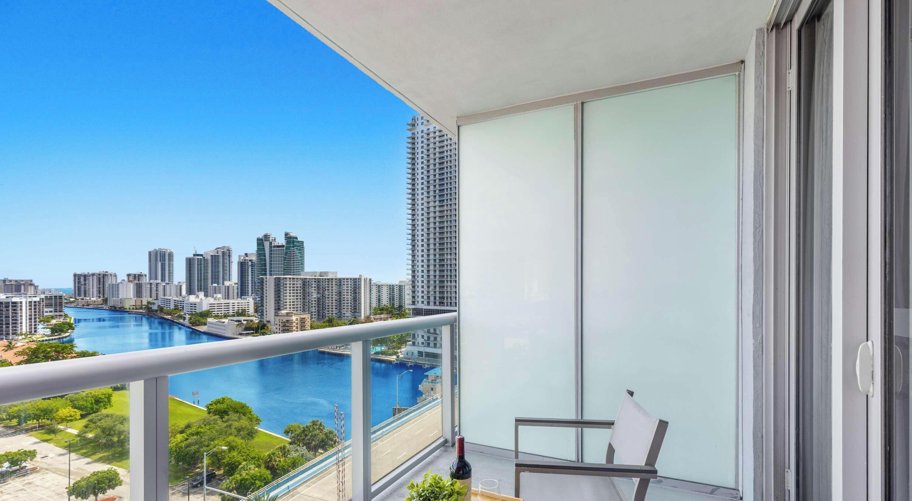 A balcony with a city view, a chair, and a bottle of wine.