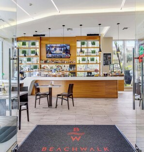A modern bar area with a TV screen, wooden counter, and seating. - Breezy Studio w/ Marina View & Balcony (Hallandale Beach)