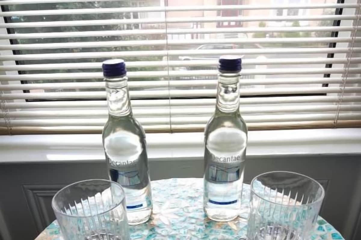 A round table with a mosaic top, two bottles of water, and two glasses.