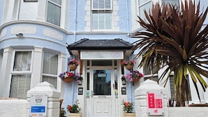 A hotel entrance with a white door, flower baskets, and a sign indicating a 4-star rating. - The Rosedene (Llandudno)