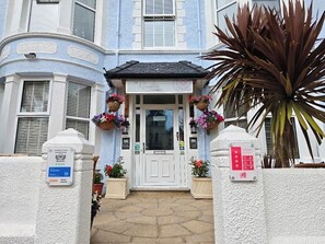 A hotel entrance with a white door, flower baskets, and a sign indicating a 4-star rating. - The Rosedene (Llandudno)