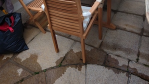 An outdoor wooden table and chairs set on a sidewalk, with a street and parked cars in the background. - The Rosedene (Llandudno)