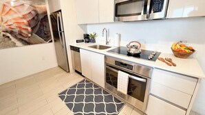 A modern kitchen with stainless steel appliances, a coffee station, and a fruit bowl. - 1BR with Stunning Intracoastal View, Private Balcony & Full Kitchen (Hallandale Beach)