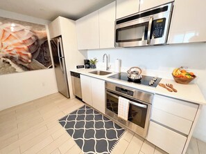 A modern kitchen with stainless steel appliances, a coffee station, and a fruit bowl. - 1BR with Stunning Intracoastal View, Private Balcony & Full Kitchen (Hallandale Beach)