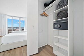 A hotel room with a bed, a wardrobe with a digital lock, and a view of the city through large windows. - Cozy Upper Studio - Beach access & Private Balcony (Hallandale Beach)