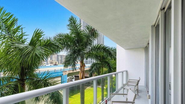 Ein Balkon mit Blick auf Palmen und ein blauen Pool.