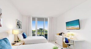 Ein Hotelzimmer mit zwei Betten, einem Schreibtisch, einem Sessel, einem Fernseher und einem Balkon mit Aussicht.