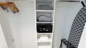 Ein weißer Stauraum mit Regalen, einem schwarzen Tresor und einer Wand mit Muster.