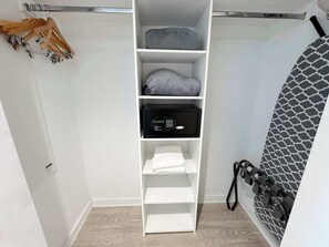 Ein weißer Stauraum mit Regalen, einem schwarzen Tresor und einer Wand mit Muster.