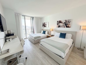 Ein Hotelzimmer mit zwei Betten, einem Schreibtisch, einem Stuhl, einem Fernseher und Bildern an den Wänden.