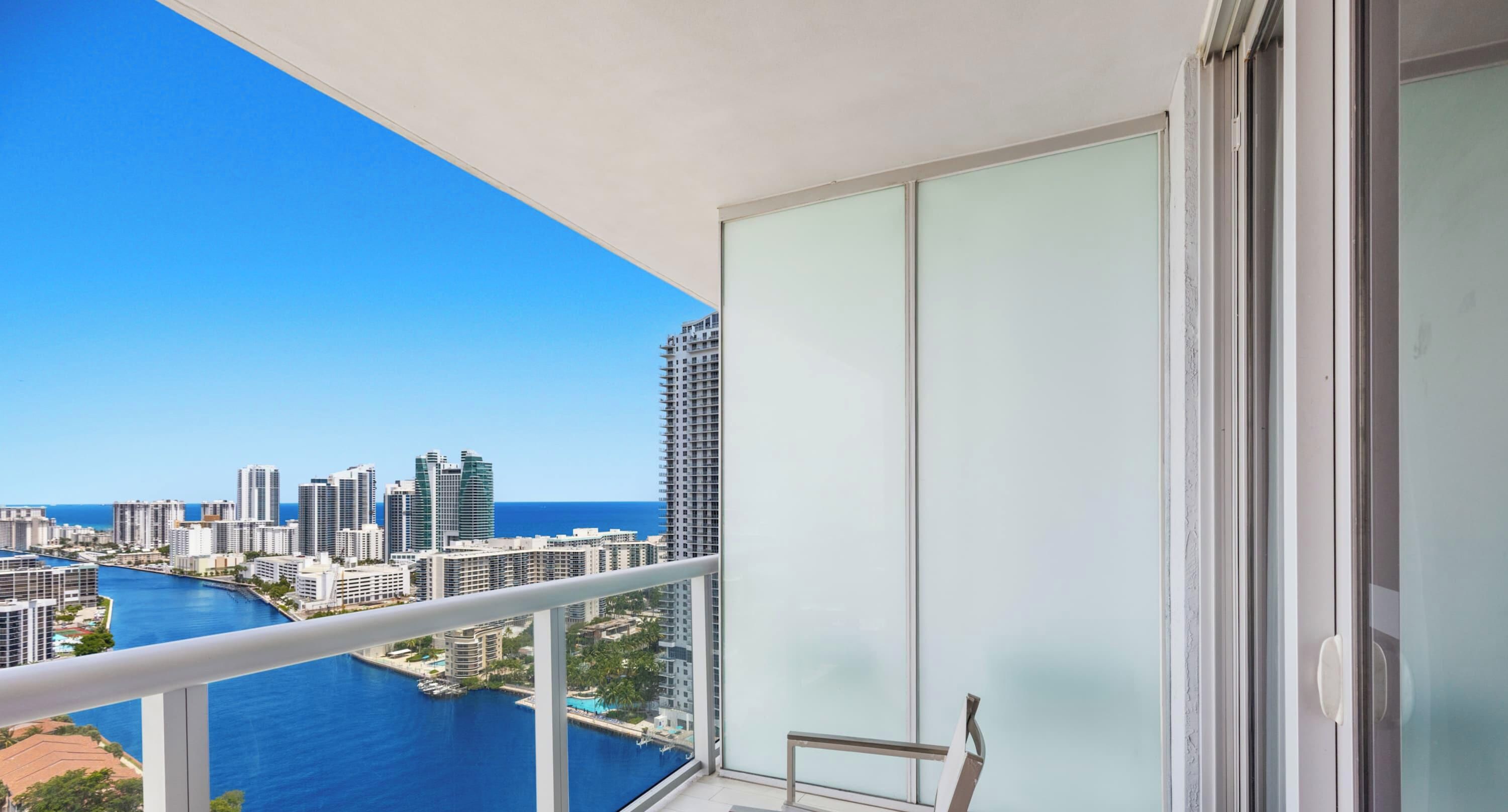 A balcony with a cityscape view, including high-rise buildings and a body of water.