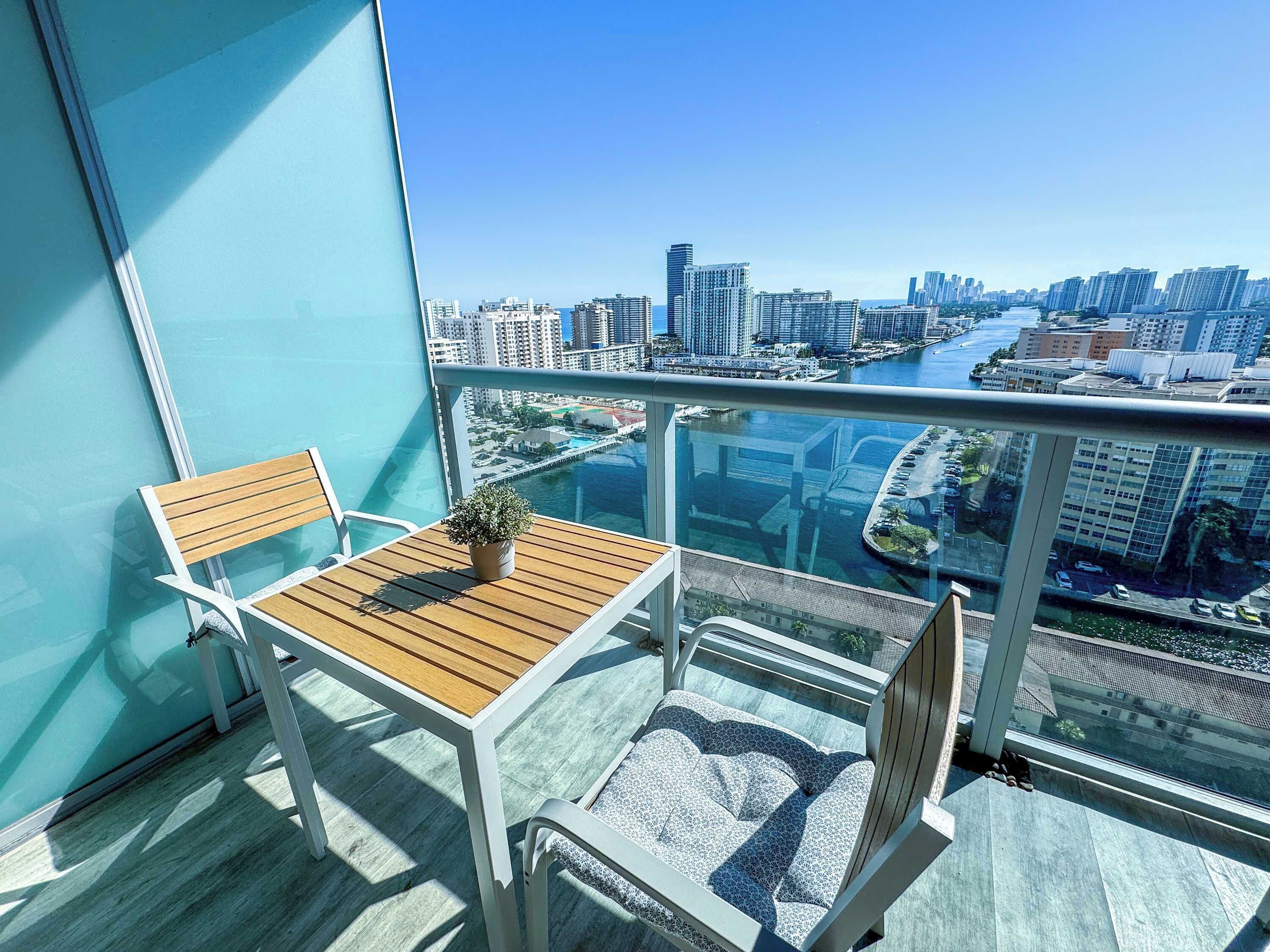 Ein Balkon mit Tisch und Stühlen, einer Topfpflanze und Blick auf die Stadt.