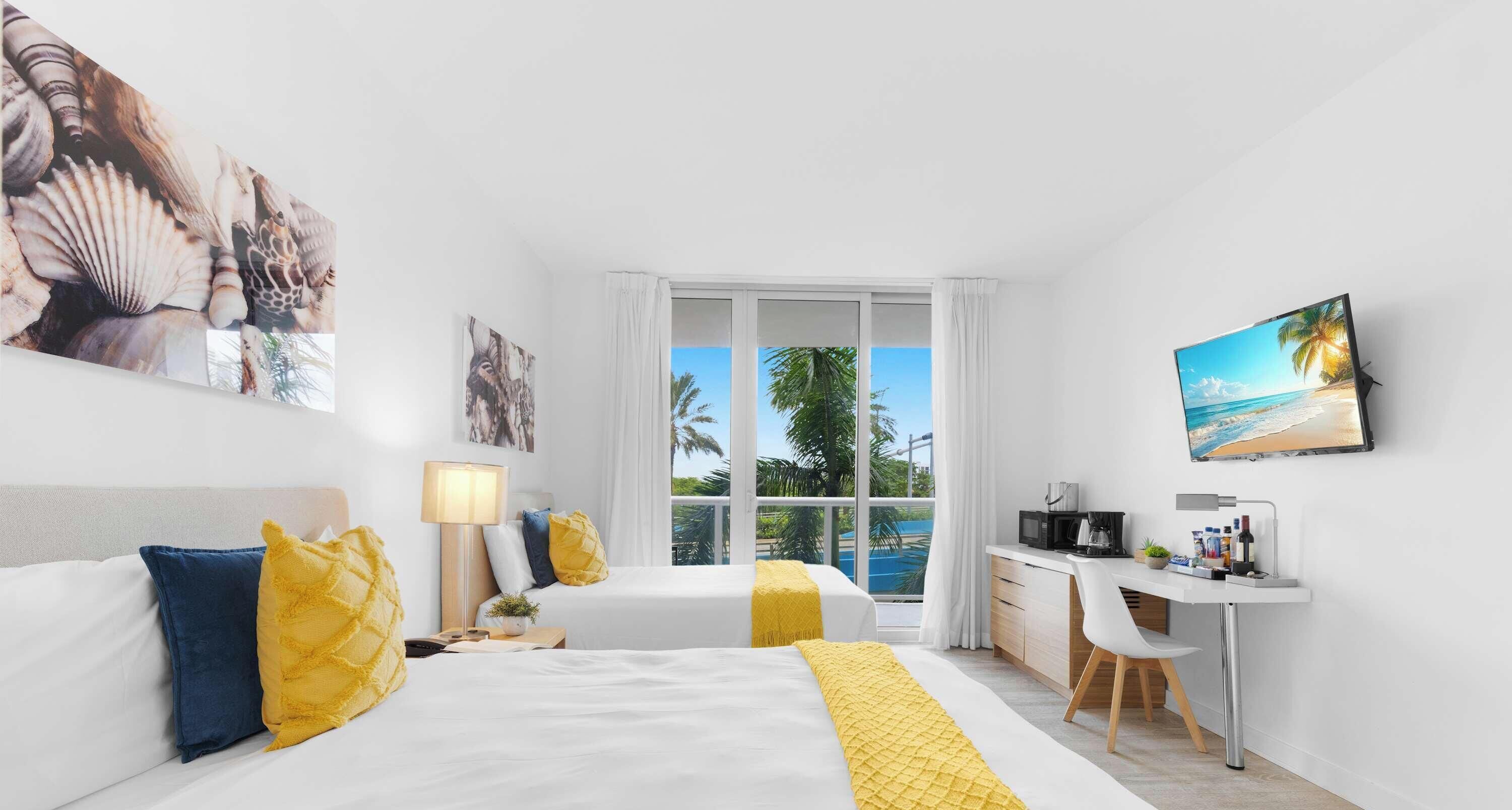A hotel room with a bed, a desk, and a view of the beach.