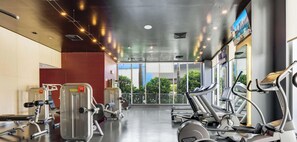 Ein Fitnessraum mit Cardiogeräten, Gewichten und großen Fenstern mit Blick ins Freie.