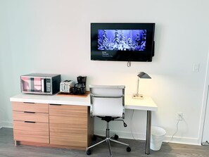 Un espace de bureau moderne comprenant un bureau, une chaise et un téléviseur fixé au mur qui diffuse une scène d’hiver.