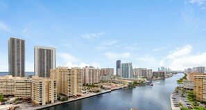 Eine Skyline am Wasser mit Hochhäusern, einem Yachthafen und wolkenlosem Himmel.
