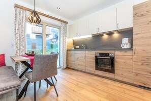 Eine moderne Küche mit Holzschränken, einem eingebauten Backofen und einer Kaffeemaschine.