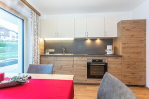 Eine moderne Küche mit Holzschränken, einem Einbauofen und einer Kaffeemaschine.