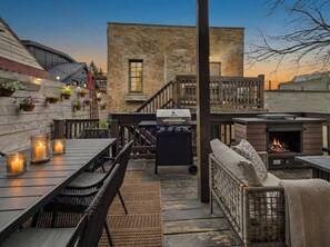 Ein Außenbereich mit Terrasse, Grill, Sitzgelegenheiten und Blick auf ein Backsteinhaus.