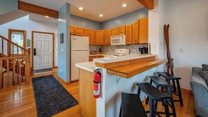 Una cocina moderna con armarios de madera, un refrigerador blanco, un microondas y una isla integrada con taburetes de bar.