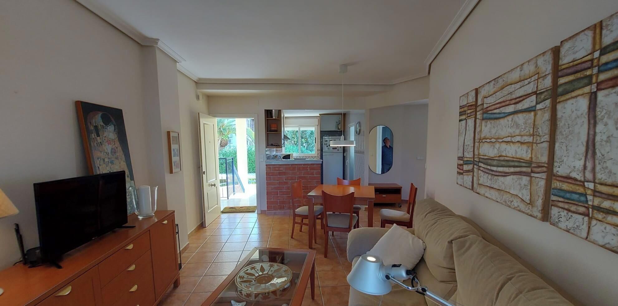 Sala de estar con televisor, sofá y comedor.