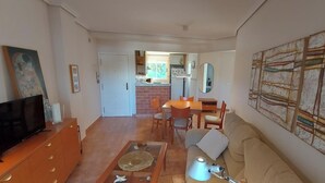 Una sala de estar con televisor, sofá, mesa de centro y una obra de arte en la pared.
