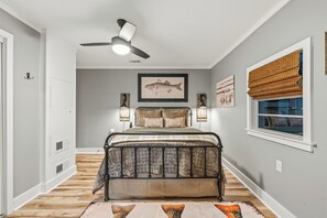 Ein Schlafzimmer mit Bett, Deckenventilator, Wandleuchten und einem Fenster mit Jalousien.