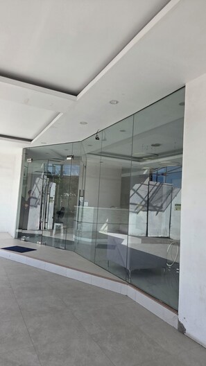 Een modern gebouw met een glazen entree, een zichtbare trap en een nette, betegelde vloer.