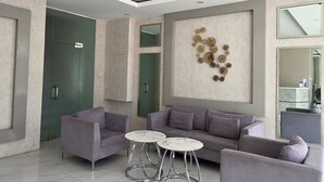 Een moderne woonkamer met een zithoek, een salontafel en een decoratief wandobject.