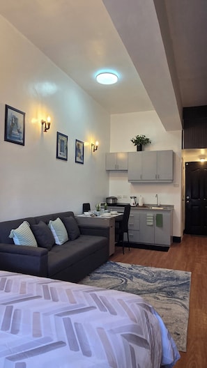 Een knus woongedeelte met een bank, een eettafel, een kitchenette en een bed.