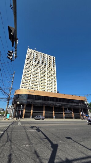 Un immeuble à plusieurs étages, doté d’une façade sobre, avec un grand parking en dessous et un ciel bleu dégagé au-dessus.
