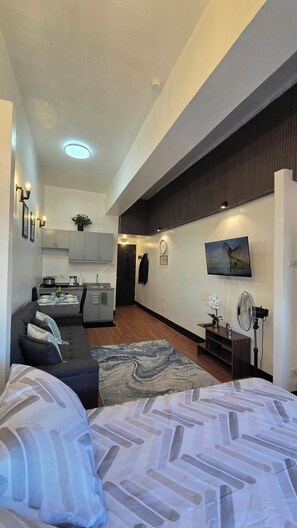 Een moderne woonruimte met een keuken, een bank, een bed en een televisie.