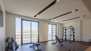 A modern gym with weightlifting equipment, a bench, and exercise balls. - LUX  The Beach Mansion Sea View Suite (Dubai)