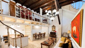 A spacious loft with a mezzanine, a dining area, a living room with a sofa, and a large painting. - Luxury Venetian Palace - Rooftop - Jacuzzi (Chania)