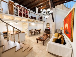 A spacious loft with a mezzanine, a dining area, a living room with a sofa, and a large painting. - Luxury Venetian Palace - Rooftop - Jacuzzi (Chania)