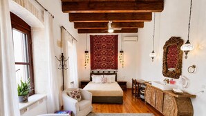 A bedroom with a bed, a chair, a desk, a mirror, and a hanging light fixture. - Luxury Venetian Palace - Rooftop - Jacuzzi (Chania)