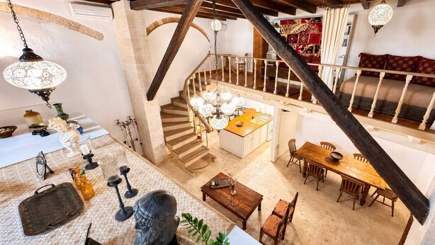 A spacious loft with a high ceiling, exposed wooden beams, a central staircase, a dining area, and a kitchen. - Luxury Venetian Palace - Rooftop - Jacuzzi (Chania)