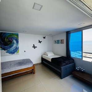 Ein Schlafzimmer mit Bett, einer Bank, einem Wandbild und einem Fenster mit Aussicht.