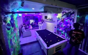 Ein Billardtisch in einem Raum mit Bar und Sitzgelegenheiten.