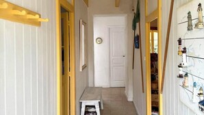 Um corredor com um banco, uma porta e uma parede decorada com tema náutico.