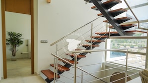 Een modern interieur met een spiltrap, een potplant en uitzicht op een zwembad.
