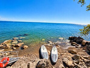 A rocky shoreline with two paddleboards and a life buoy. - Lakefront Wellness Retreat - Sauna + Cold Plunge + Paddleboards + Lake Access (Kingsville)