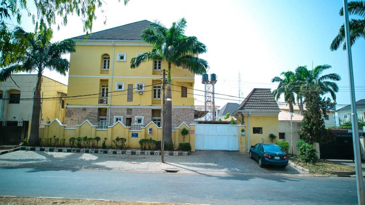 A two-story yellow building with a gated driveway and a parked car.
