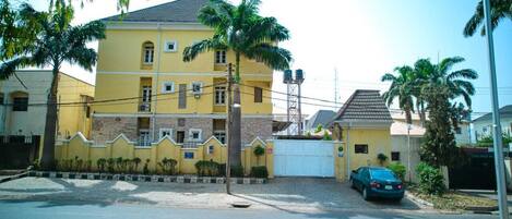 A two-story yellow building with a gated driveway and a parked car.