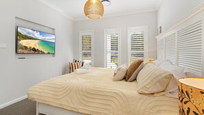 A bedroom with a bed, a TV, and a window with blinds. - Poppy's - Fire Pit - 4 Mins Walk to Beach (Callala Beach)